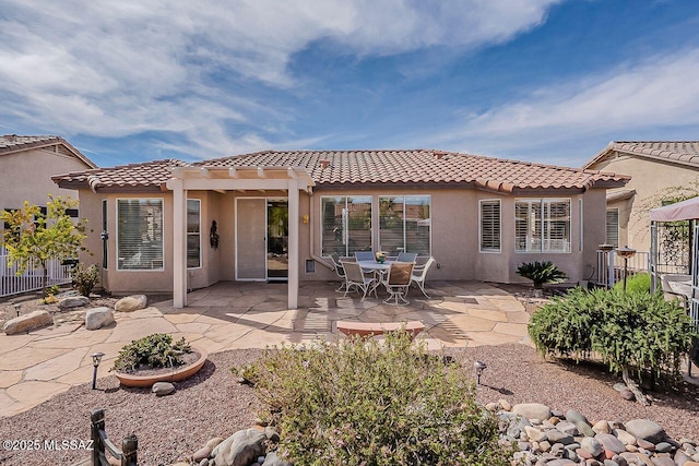 rear view of house with fence, a tiled roof, stucco siding, a pergola, and a patio area