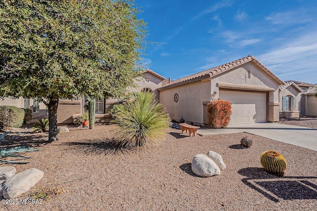 view of front of house with a tiled roof, a garage, driveway, and stucco siding