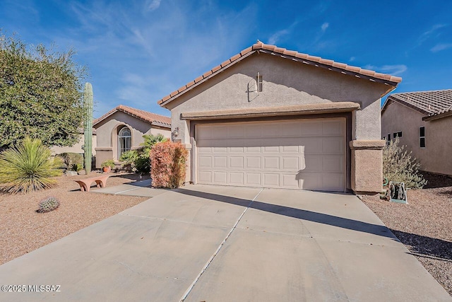 mediterranean / spanish-style home with a tile roof, stucco siding, an attached garage, and concrete driveway