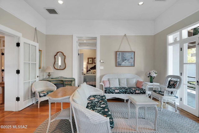 living room with recessed lighting, visible vents, and wood finished floors