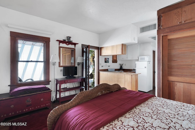 bedroom featuring visible vents and freestanding refrigerator