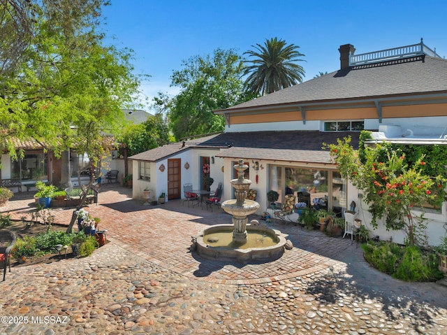 back of property with a patio area, stucco siding, and roof with shingles