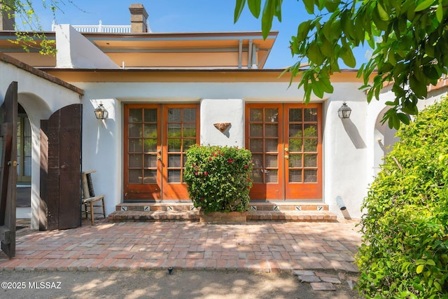 entrance to property featuring french doors and stucco siding