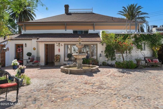 back of house with a patio area, a shingled roof, and stucco siding