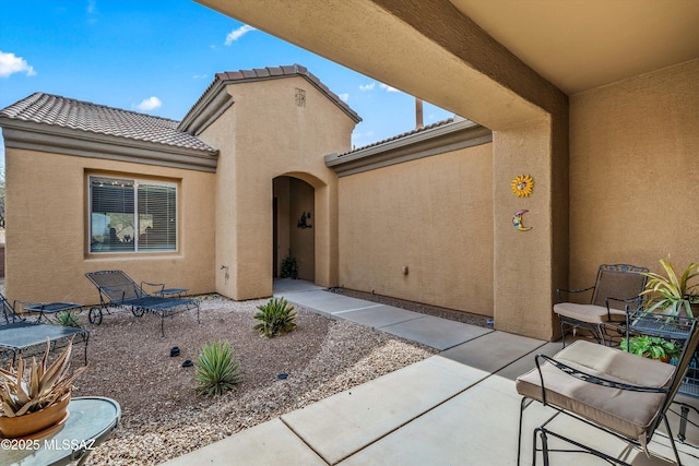 property entrance featuring a tile roof, stucco siding, and a patio area