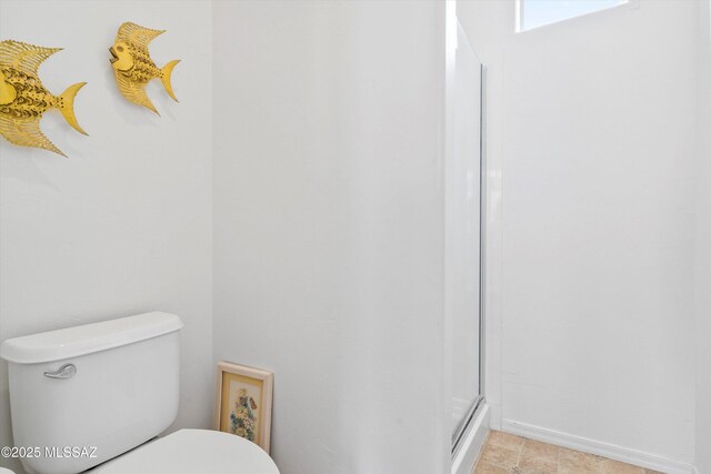 bathroom featuring toilet and a shower with shower door
