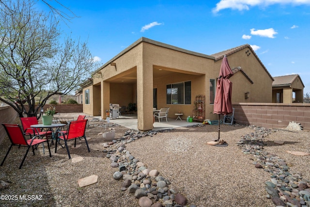 back of property featuring fence, a tiled roof, stucco siding, and a patio