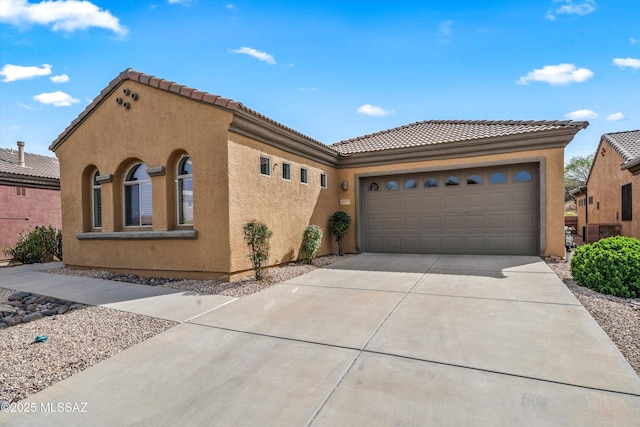 view of front facade featuring driveway, stucco siding, a tile roof, and a garage