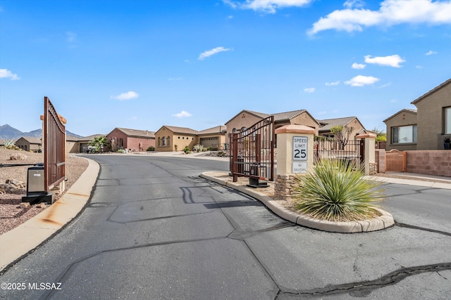 view of street with a gate, curbs, a residential view, sidewalks, and a gated entry