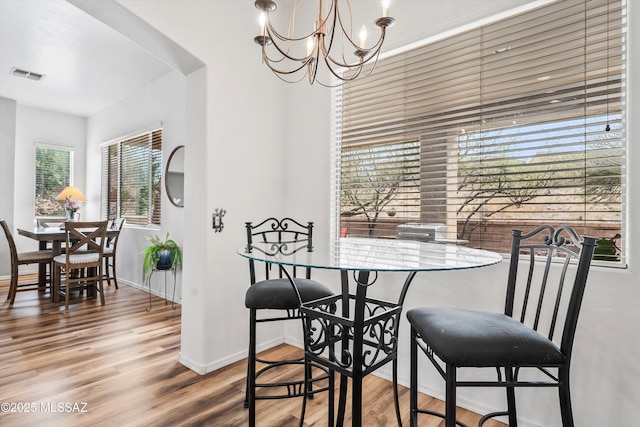 dining area with baseboards, visible vents, wood finished floors, and a chandelier