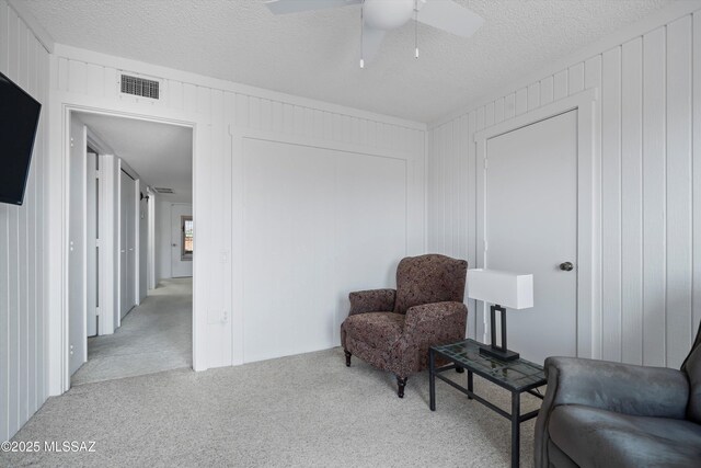 sitting room featuring a textured ceiling, carpet flooring, ceiling fan, and visible vents