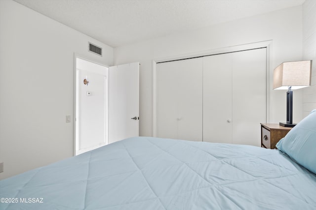 bedroom with a textured ceiling, a closet, and visible vents
