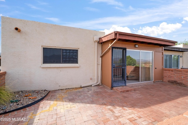 back of property with stucco siding and a patio
