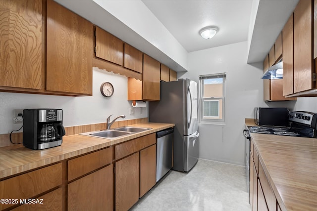 kitchen featuring under cabinet range hood, wooden counters, a sink, appliances with stainless steel finishes, and brown cabinets