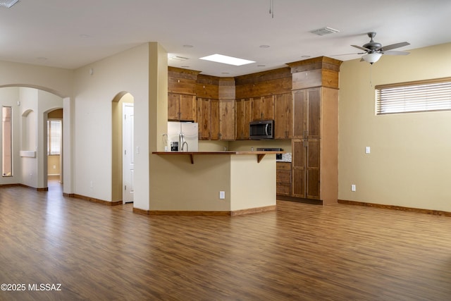 kitchen featuring dark wood-type flooring, a kitchen bar, stainless steel appliances, and a peninsula