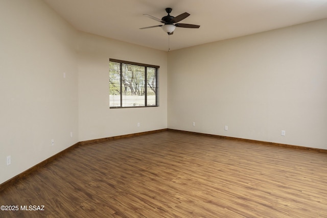 empty room with baseboards, wood finished floors, and a ceiling fan