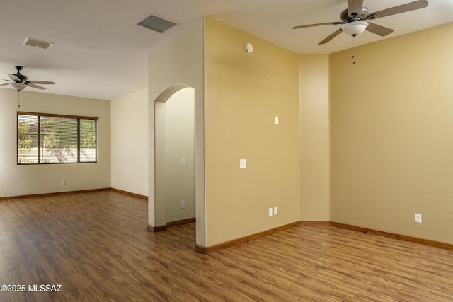 spare room with wood finished floors, visible vents, arched walkways, and ceiling fan