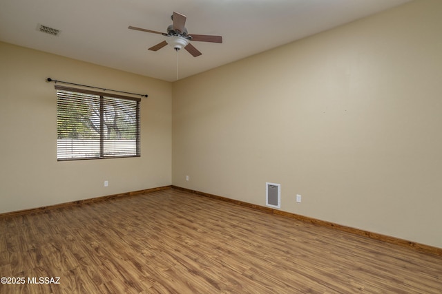 empty room featuring light wood-style flooring, ceiling fan, and visible vents