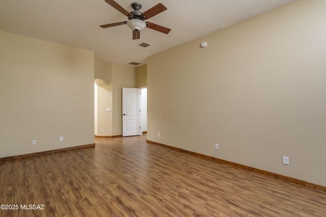 spare room with baseboards, visible vents, ceiling fan, and wood finished floors