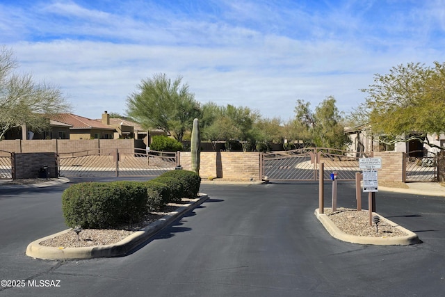 view of road featuring a gated entry, a gate, and curbs