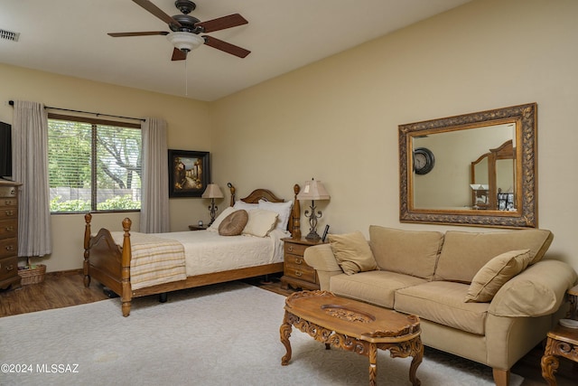bedroom featuring a ceiling fan, visible vents, baseboards, and wood finished floors