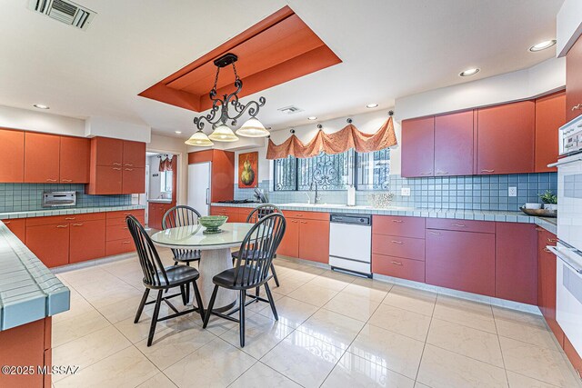 kitchen featuring white appliances, visible vents, a tray ceiling, and decorative backsplash