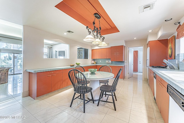kitchen featuring tasteful backsplash, decorative light fixtures, visible vents, and dishwasher