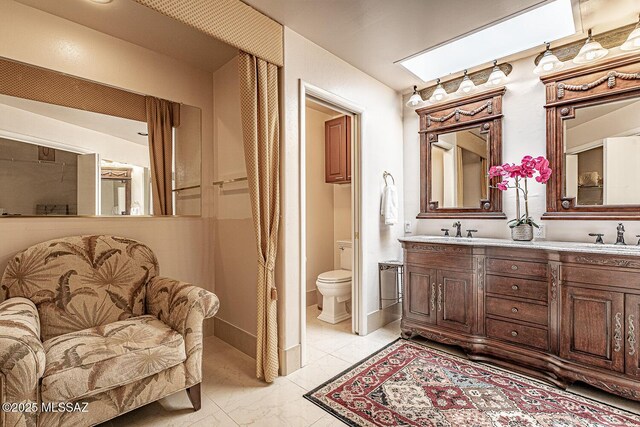 bathroom with a sink, toilet, and double vanity