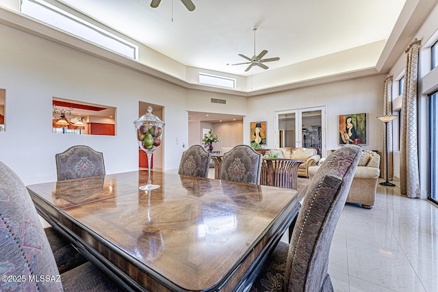 dining space with a high ceiling, marble finish floor, and ceiling fan
