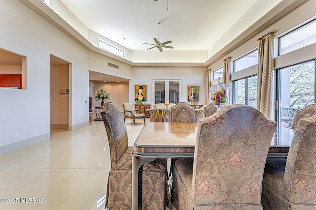 dining room featuring light tile patterned floors, ceiling fan, a towering ceiling, visible vents, and baseboards