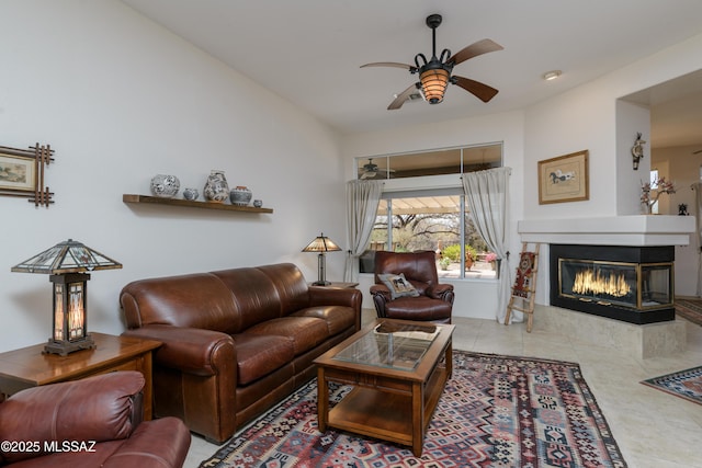 living area featuring tile patterned flooring, a ceiling fan, and a multi sided fireplace