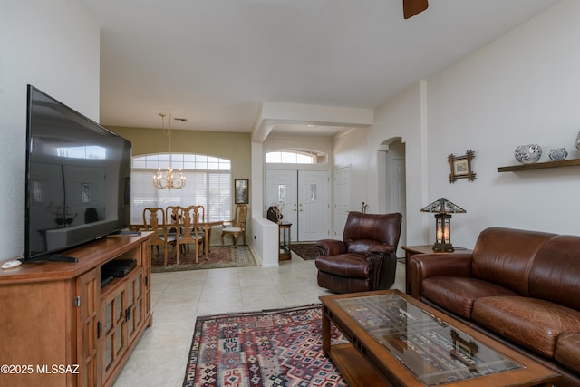 living area featuring light tile patterned floors, arched walkways, and a notable chandelier