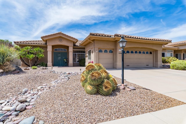 mediterranean / spanish-style home with an attached garage, stucco siding, a tile roof, and concrete driveway