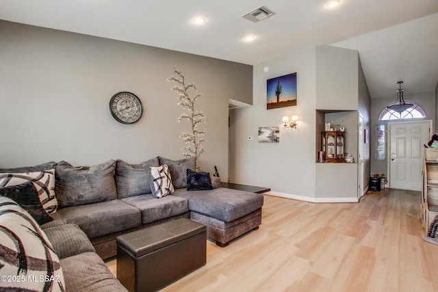 living area featuring lofted ceiling, light wood-type flooring, recessed lighting, baseboards, and visible vents