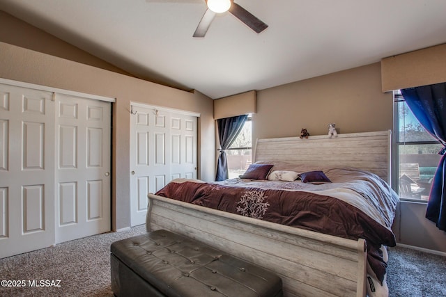 bedroom with ceiling fan, vaulted ceiling, two closets, and carpet floors
