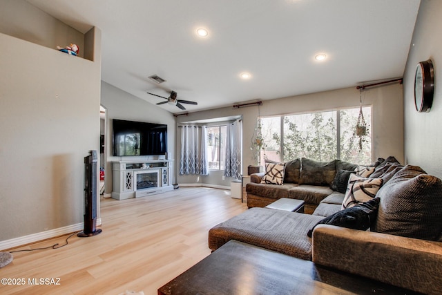 living area with lofted ceiling, ceiling fan, visible vents, a fireplace, and wood finished floors