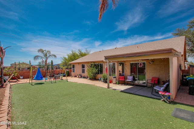 back of house featuring a fenced backyard, a lawn, stucco siding, and a patio