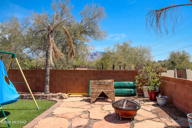 view of patio / terrace with a fire pit, a fenced backyard, and a playground