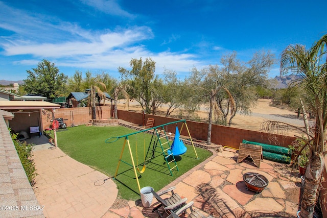 exterior space featuring an outdoor fire pit, a fenced backyard, and a playground