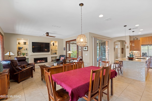 14082 N Tiyo Point Trl, Marana, AZ 85658 - dining space with a warm lit fireplace, light tile patterned floors, built in features, and arched walkways