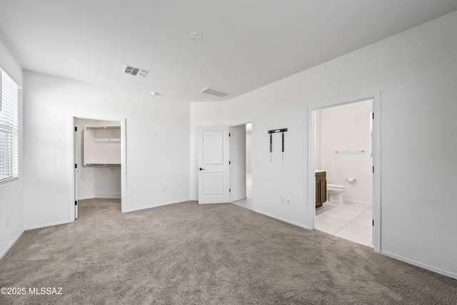 unfurnished bedroom with visible vents, a spacious closet, carpet flooring, and connected bathroom