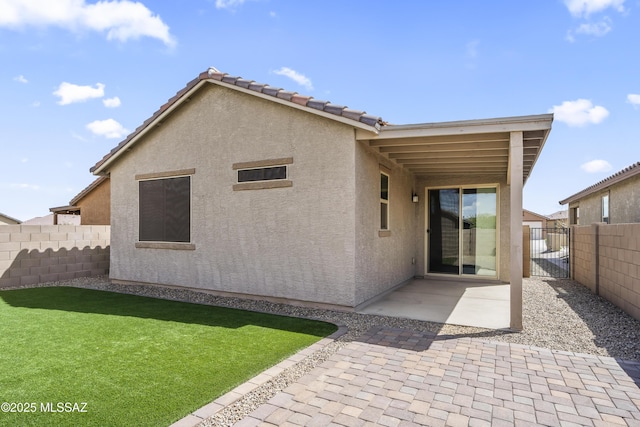 back of property with a tiled roof, stucco siding, a lawn, a patio area, and fence