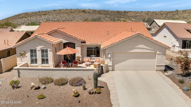 view of front of house featuring driveway, a tile roof, a garage, and stucco siding