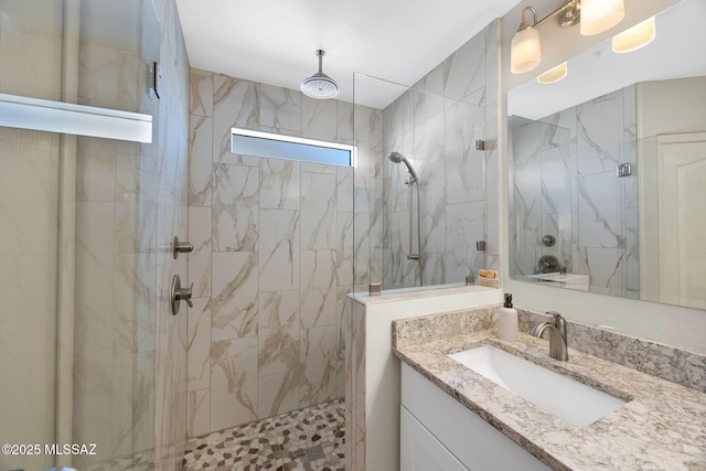 full bathroom featuring a marble finish shower and vanity