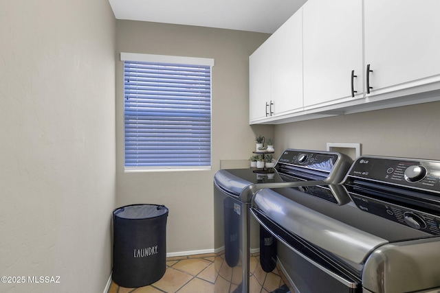 laundry area with washing machine and clothes dryer, baseboards, cabinet space, and light tile patterned floors