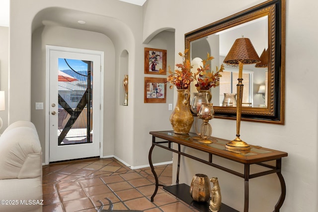foyer entrance with tile patterned floors, baseboards, and arched walkways