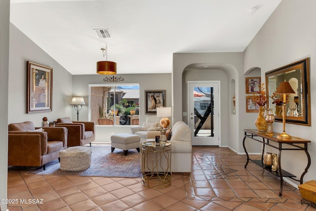 living area with arched walkways, light tile patterned floors, and visible vents