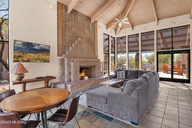 6655 N Canyon Crest Dr Unit 23102, Tucson, AZ 85750 - living area with wood ceiling with exposed beams, stone tile flooring, a fireplace, a ceiling fan, and high vaulted ceiling
