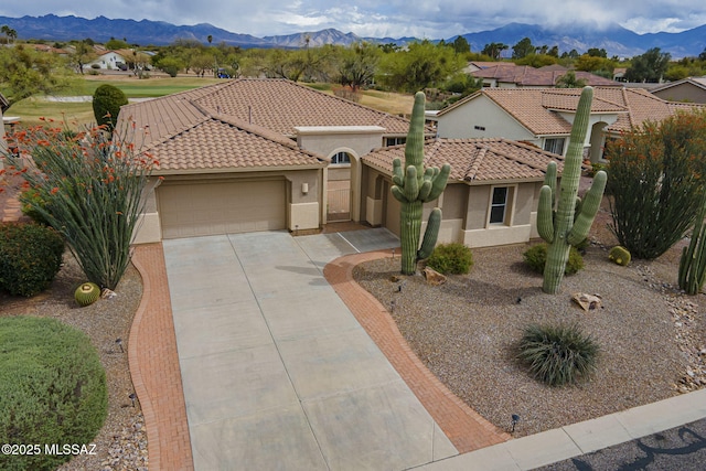 mediterranean / spanish-style house featuring a tiled roof, concrete driveway, a garage, and a mountain view