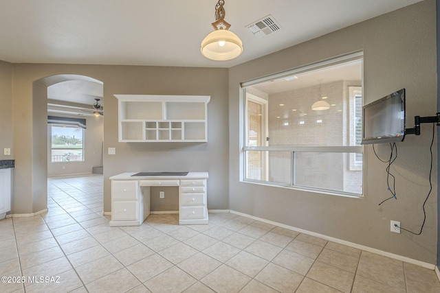 unfurnished office featuring arched walkways, ceiling fan, visible vents, and light tile patterned floors